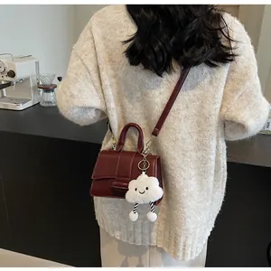 Detailed view of vintage burgundy leather crossbody bag with cute cloud plush charm detail