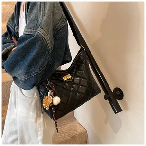 Détail d'un sac bandoulière noir matelassé avec fermoir doré et breloque baseball