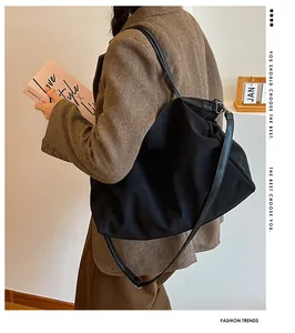 Detail of a large black tote bag featuring a pleated texture and soft glossy finish
