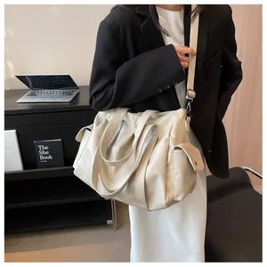 Détail du grand cabas en cuir blanc cassé avec bandoulière réglable et poche latérale
