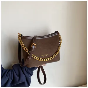 Detailed close-up of dark brown suede bucket bag with gold chain and leather handle
