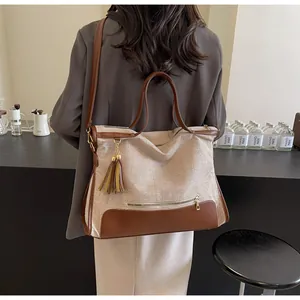 Détail du grand sac cabas tissé avec garniture en cuir marron et pompon sur un mannequin