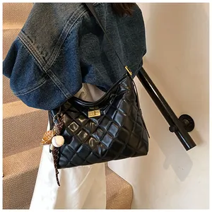 Détail du sac à bandoulière matelassé noir avec fermoir doré et breloque baseball