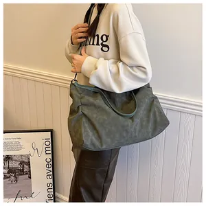 Deep green oversized tote bag with adjustable strap shown on model in a minimalist setting