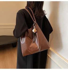 Close-up of the embossed logo and baseball charm on this brown PU leather tote bag