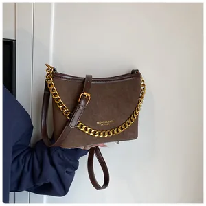 Close-up of brown suede and leather bucket bag with gold chain strap and branding