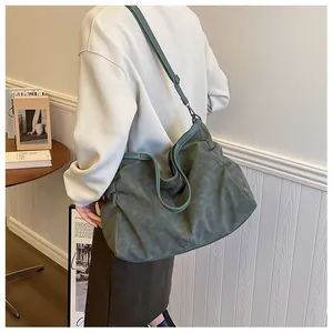 Detail of a large dark green hobo bag with vintage suede texture and adjustable straps