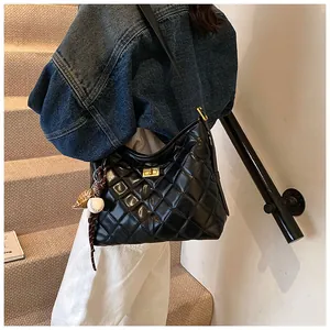 Détail du sac hobo en cuir matelassé noir avec fermoir doré et breloques de sac