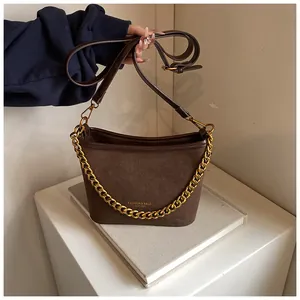 Detail view of brown suede bucket bag featuring gold chain and FASHION lettering