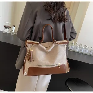 Détail d'un grand sac cabas tissé avec finitions en cuir marron et pompon décoratif