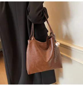 Close-up of brown tote bag featuring marbled leather texture and a baseball charm