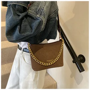 Detail of dark brown suede bucket bag with gold chain strap and fashion logo