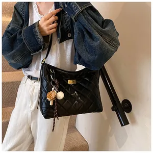 Détail du sac à bandoulière noir matelassé avec fermoir doré et breloque baseball sur modèle