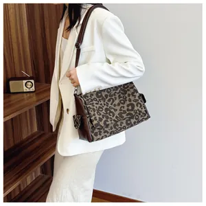 Close-up of leopard print tote bag with brown leather straps worn with a white blazer