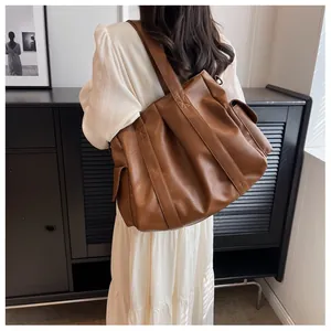 Grand sac cabas marron avec poches latérales et sangles renforcées porté par mannequin