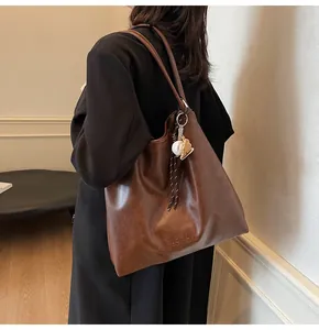 Detailed view of mocha brown leather tote bag featuring a baseball and bear charm