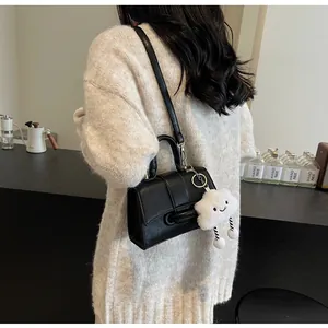 Detail of black faux leather shoulder bag with a cute white cloud plush pendant