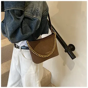 Detail of dark brown matte shoulder bag with chunky gold chain strap and embossed lettering