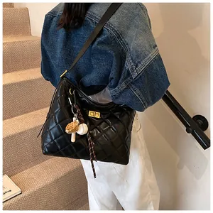Détail du sac bandoulière noir matelassé avec fermoir doré et breloque baseball