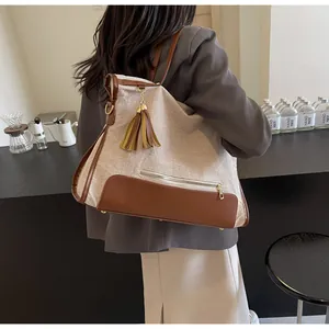 Détail d'un grand sac cabas en toile kaki avec garniture en cuir marron et pompon