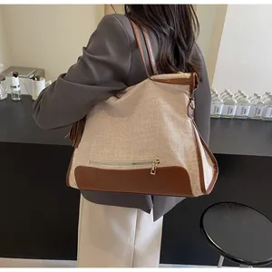 Détail du sac cabas tissé avec garniture en similicuir marron et pendentif à pompon décoratif