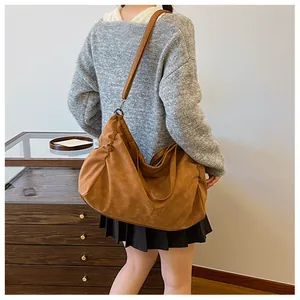 Rear view of a model wearing a large brown hobo bag with wide strap and matte texture