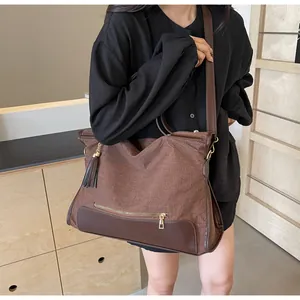 Detail of large canvas tote with brown leather stitching and decorative metal zipper