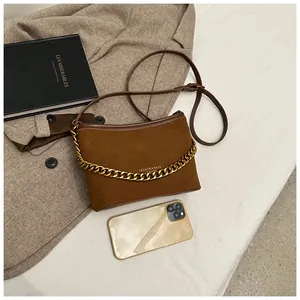 Detailed view of a brown suede shoulder bag with gold chain and matching coat