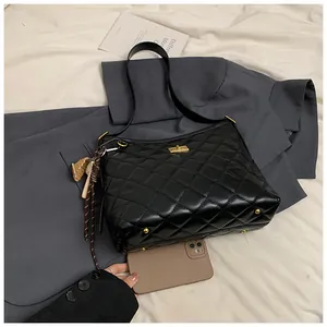 Détail du sac bandoulière matelassé noir avec fermoir doré et pieds en métal