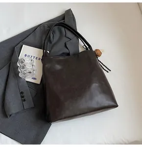 Detail of mocha brown tote bag featuring matte leather texture and a cute bear charm