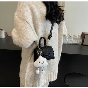 Close-up of black PU leather crossbody bag with a plush white cloud charm and strap
