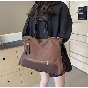 Détail d'un sac cabas tressé marron avec pompon en cuir et fermeture éclair en métal