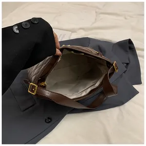 Détail de l'intérieur d'un sac bandoulière matelassé marron avec finitions dorées