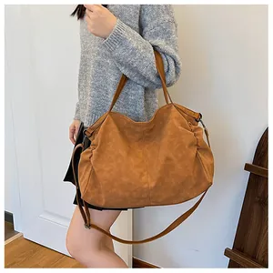 Caramel brown hobo tote bag in matte leather finish being carried by a model