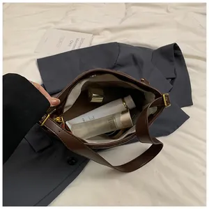 Vue détaillée de l'intérieur spacieux d'un sac en cuir marron avec divers cosmétiques