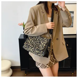 Detailed view of leopard print crossbody bag with black leather strap and metal buckles