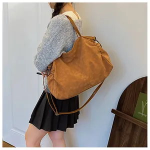 Detail of a large brown suede tote bag worn cross-body with adjustable strap on a model