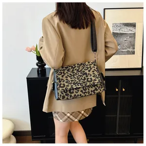 Rear view of a model wearing the leopard print crossbody bag with wide black shoulder strap