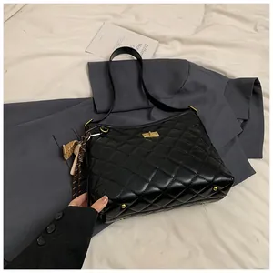 Détail du sac matelassé noir avec fermoir doré tournant et pendentif décoratif