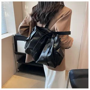 Détail du grand sac cabas noir avec design plissé et large bandoulière porté par le modèle
