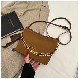 Macro shot of brown suede bucket bag with gold chain strap and elegant leather texture