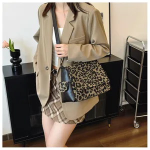 Detail of leopard print flap and black leather stitching on a stylish crossbody tote bag