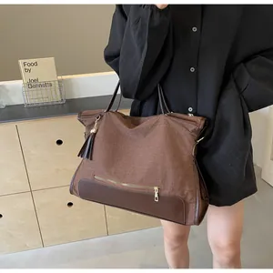 Détail du sac cabas tissé avec cuir marron et breloque à pompon élégante