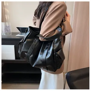 Vue latérale du grand sac cabas noir en similicuir avec poche et large bandoulière