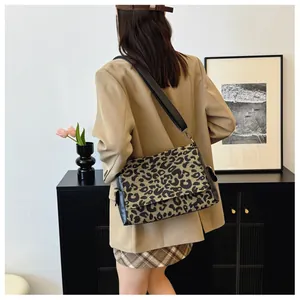 Close-up of leopard print crossbody bag featuring black leather trim and wide fabric strap