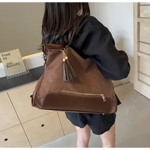 Détail d'un grand sac cabas marron et beige avec pompon porté par un mannequin