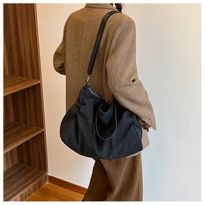 Detail of the black canvas tote bag showing the faux leather strap and metal ring