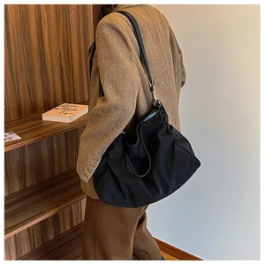 Side view of a large black nylon tote bag worn with a stylish brown herringbone blazer