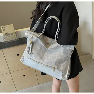 Détail d'un grand sac cabas tissé gris avec sangles bleu clair et pompon doré zippé