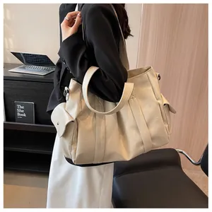 Détail d'un grand sac fourre-tout en cuir beige avec poches extérieures et anses larges